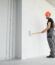 Male workers doing interior renovation in apartment. Portrait of happy smiling confident adult man wall painter in white uniform holding paint roller and tray standing by step ladder looking at camera